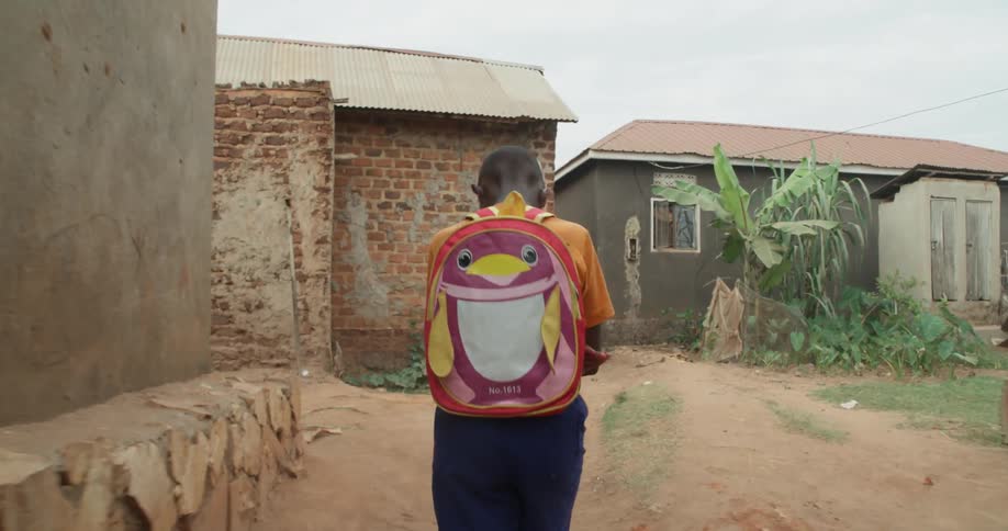 A boy with a backpack walks down an alley