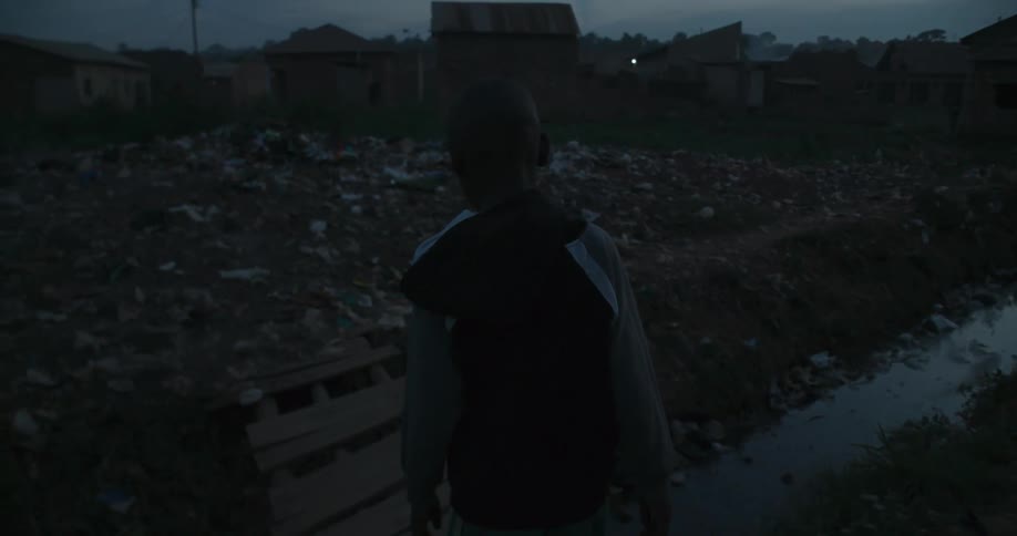 Child walks over stony garbage filled land