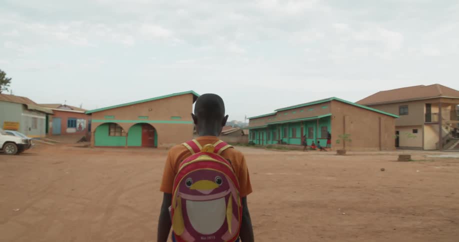 A child wearing a backpack walks across a parking lot
