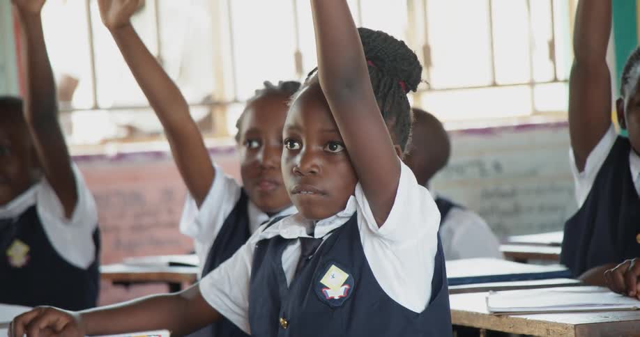 Children raise their hands in a classroom