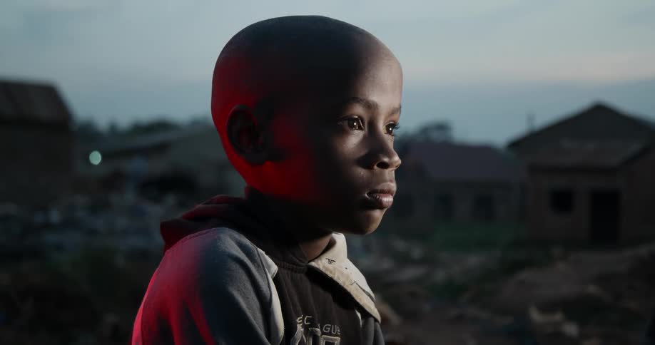 A boy sits in his yard looking ahead
