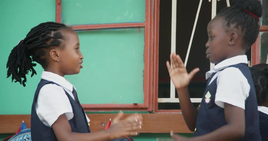 Two young girls are playing a clapping game