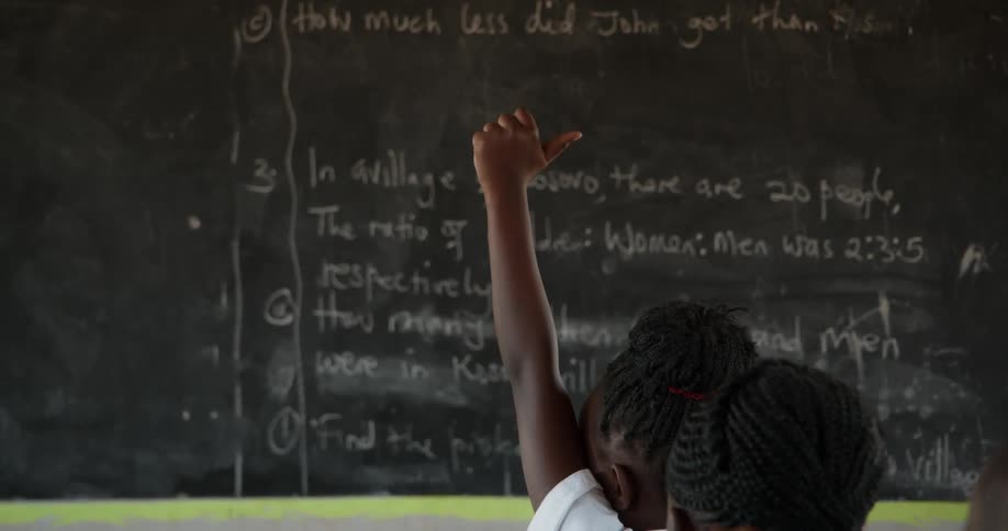 A student raises her hand in a classroom