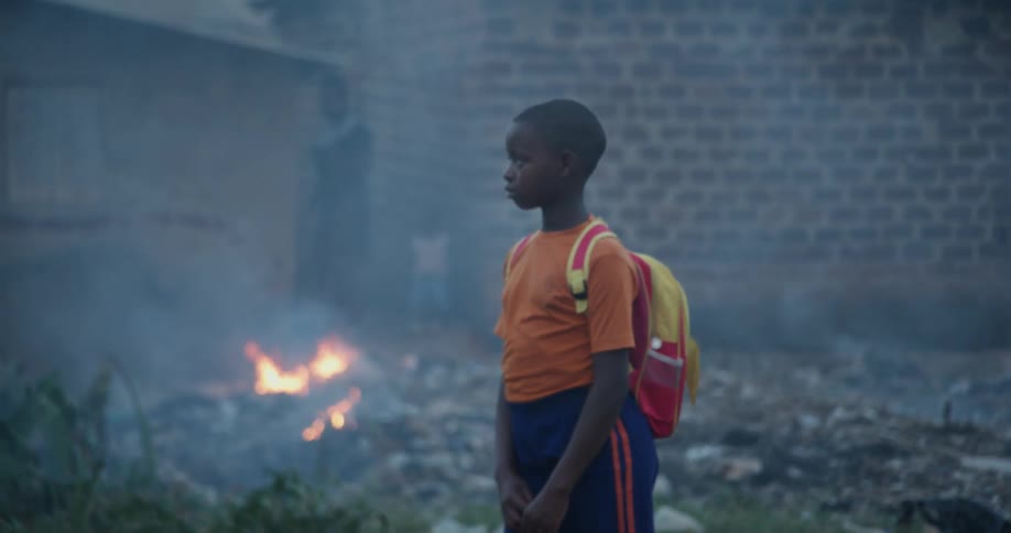A boy wearing a backpack near a fire