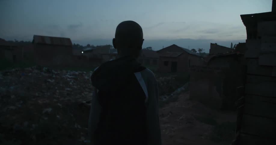 A boy is walking in his village at dawn