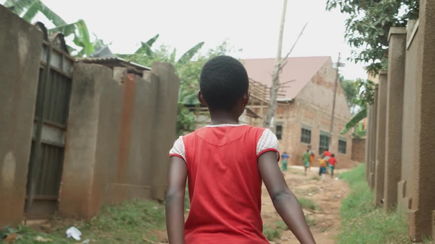 Child walks in a village towards a group of children