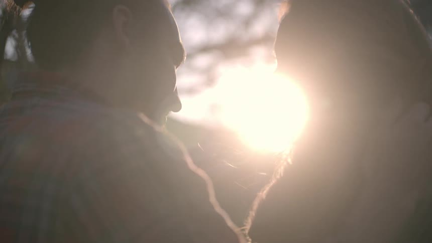 A man and woman laugh and cuddle in the forest