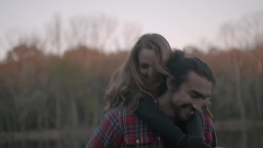 A man and a woman play around near a pond