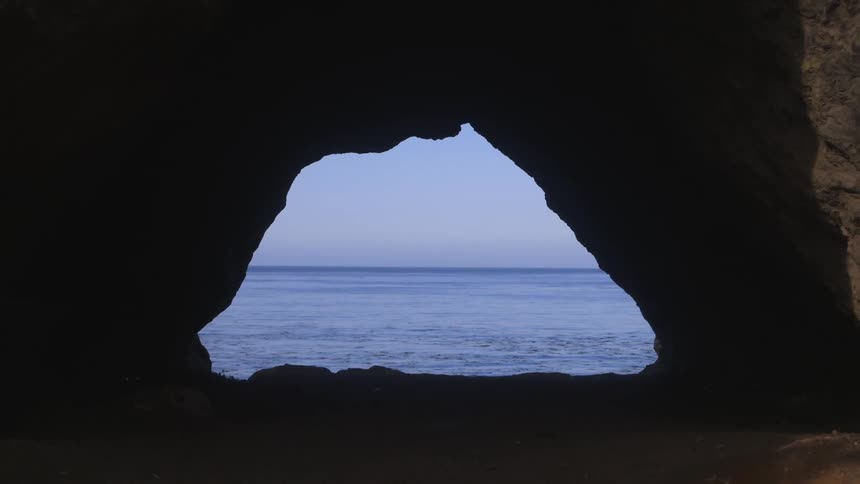View looking through a cave out into the water