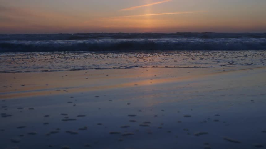 Oceans waves crashing in on beach after sunset