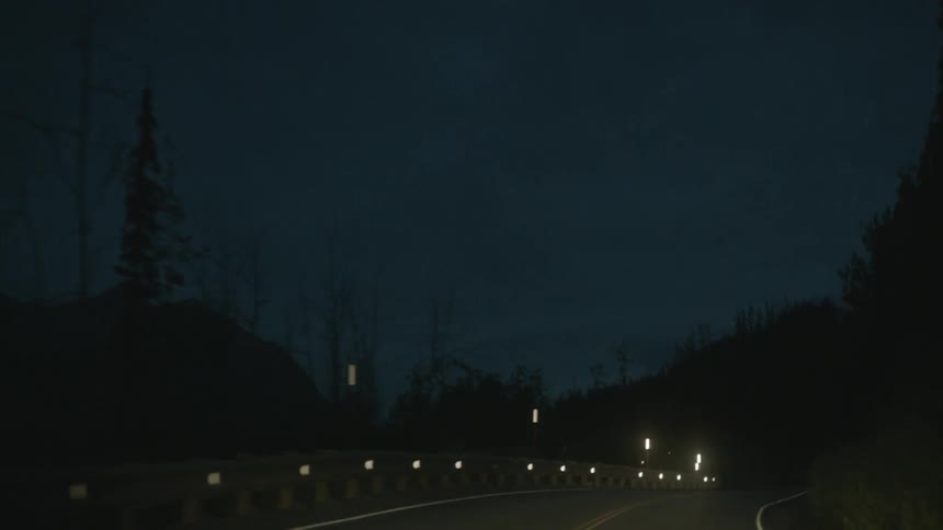 A vehicle drives on a mountain road at night
