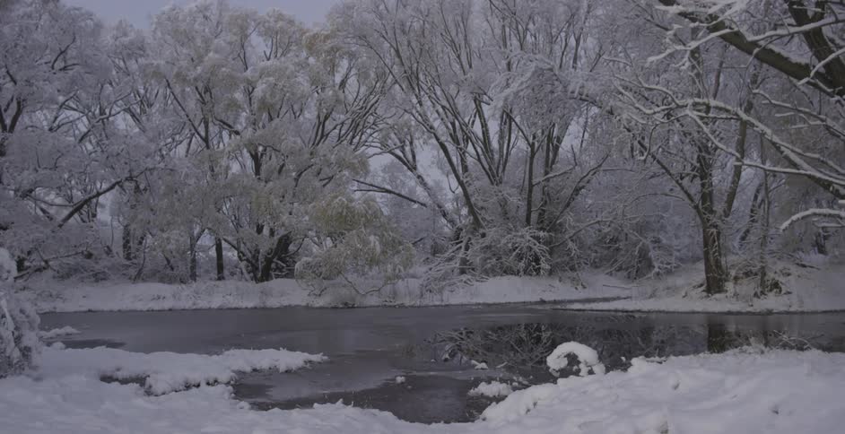 Snow covers the shoreline to a partially frozen lake