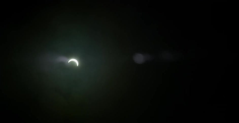 Clouds pass by the half circle moon in the night sky