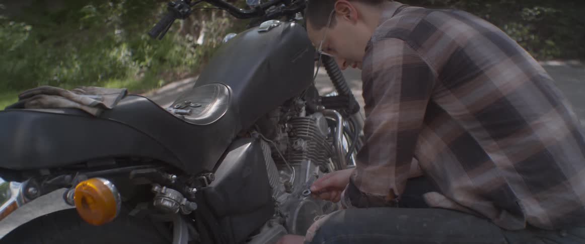 Man working on a motorcycle on the side of a road