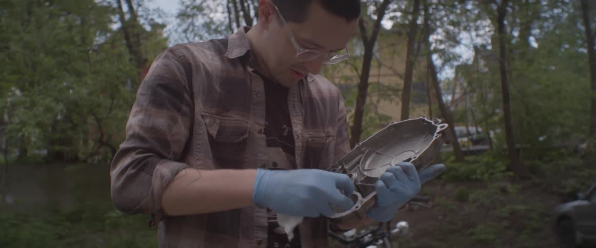 Man cleans off a piece of metal with a rag