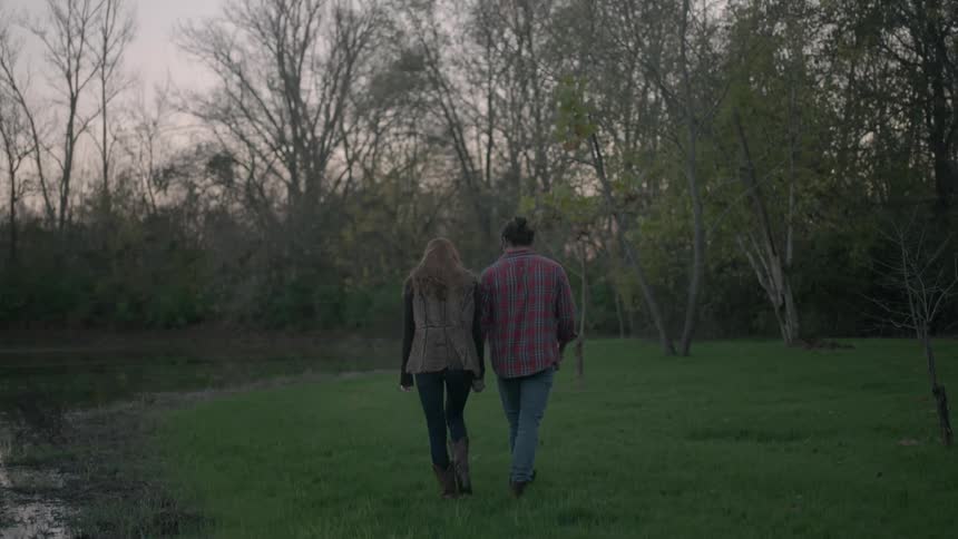 A man and woman wallk in a grassy field