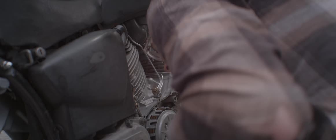 Man wearing blue gloves scrapes at a machine