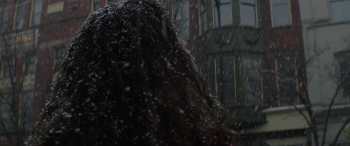 A woman looks around as it snows around her