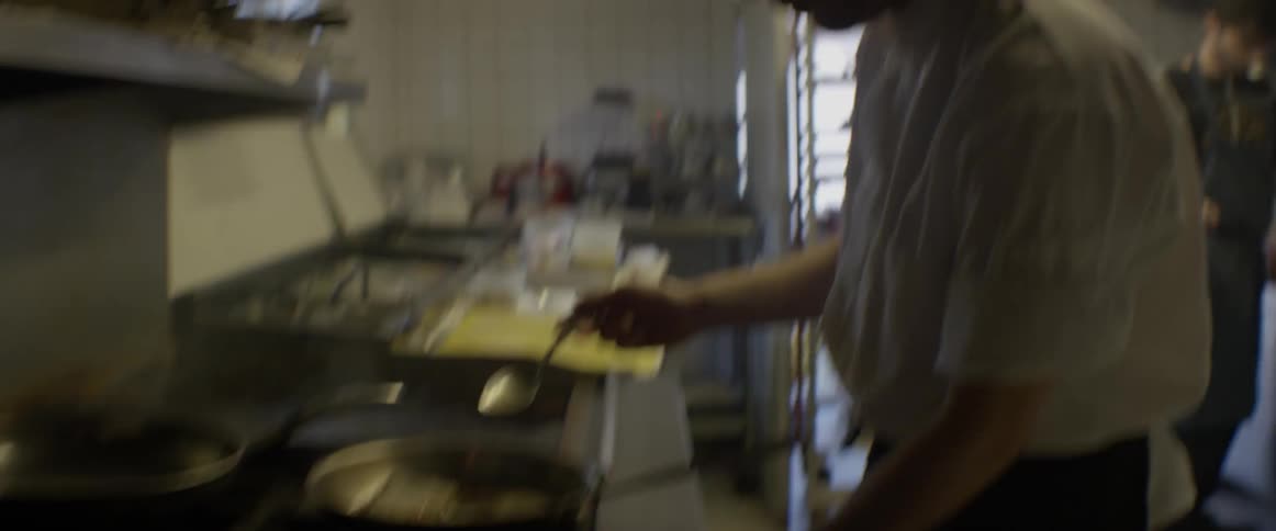 A chef is stirring ingredients in a pan in on a stove