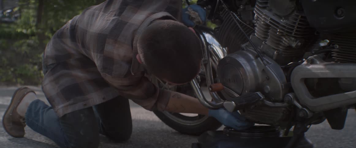 A man is changing the oil on his motorcycle