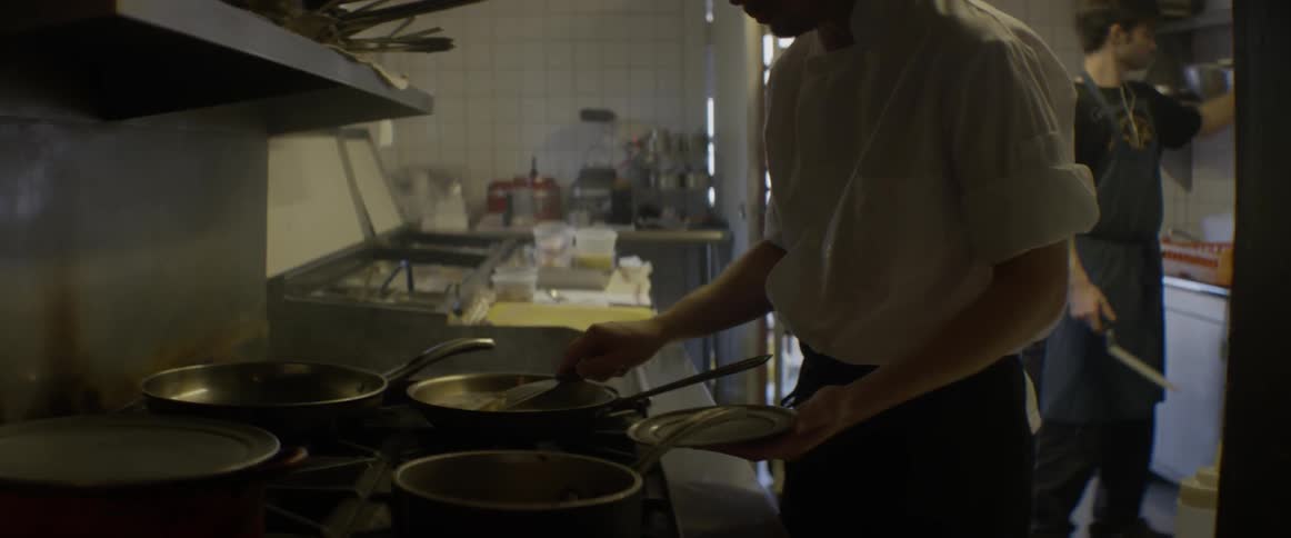A chef is removing a piece of food from a pan