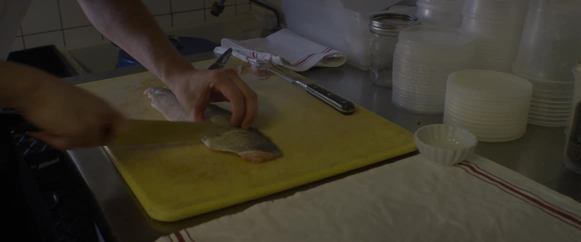 A person slices fish on a cutting board