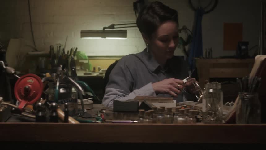 A woman works in a shop with tools and devices