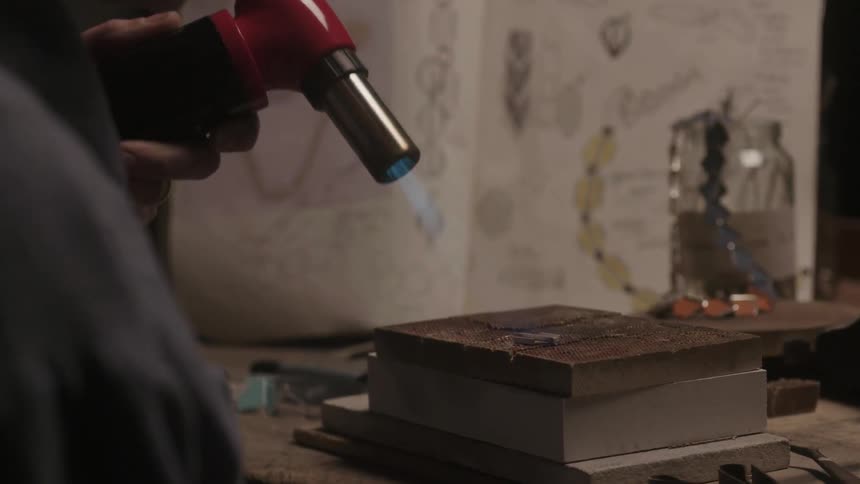 Man using a heat gun to work on material indoors