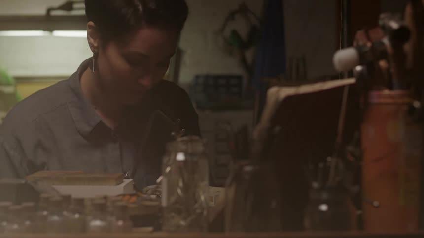 A woman props a book up as she sits down to craft something