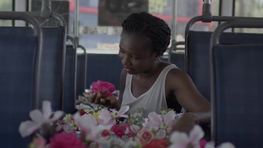A woman sits in a bus with flowers filling the aisle