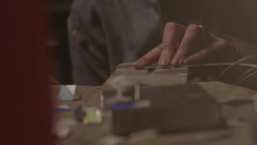 Person working on a craft using a hand tool indoors