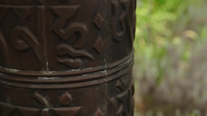 A metal bell lies by the grass