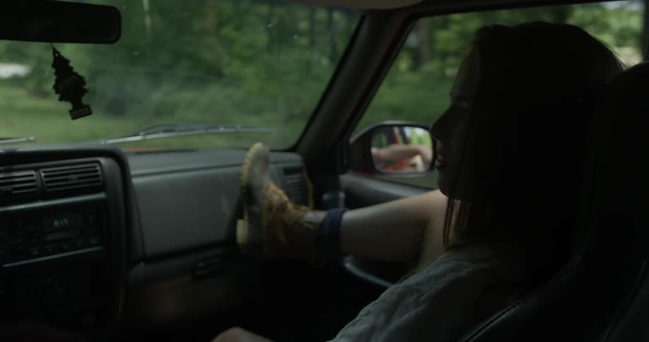 A girl riding in a vehicle sits with a foot on the dashboard