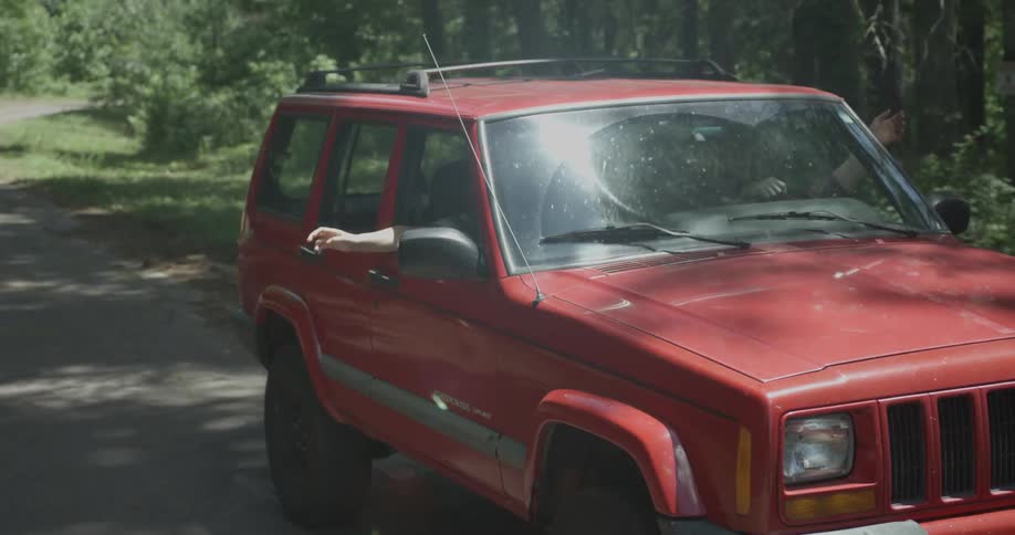 A passenger holds their arm out the window of a moving jeep