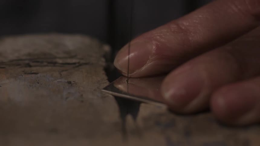 A person is cutting a piece of metal