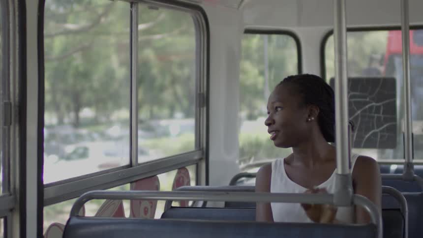 Woman sits  down on a bus and looks out the window