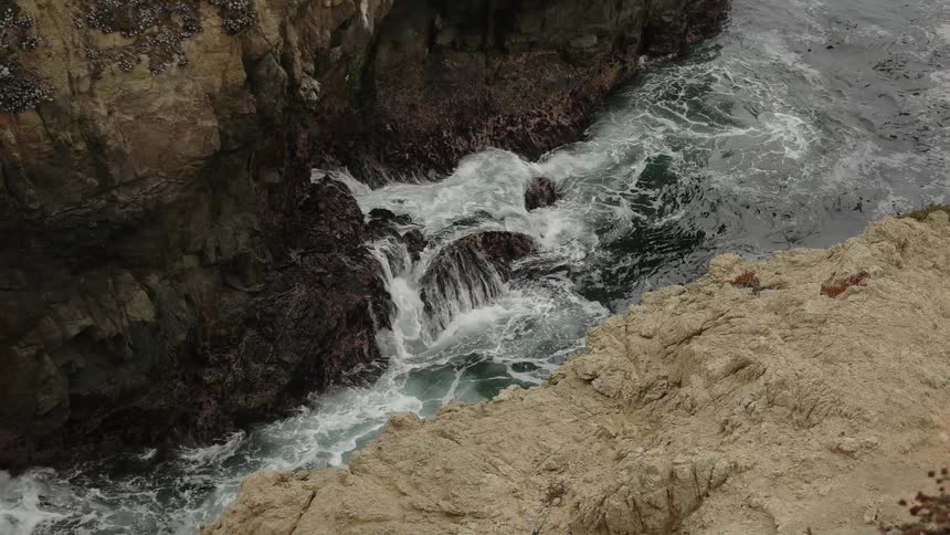 The water is splashing against the rocks below