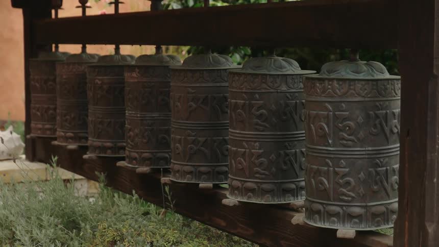 Prayer wheels hang in a row outside