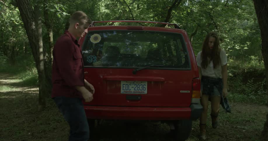A man and woman are getting out of their suv and heading towards the trunk