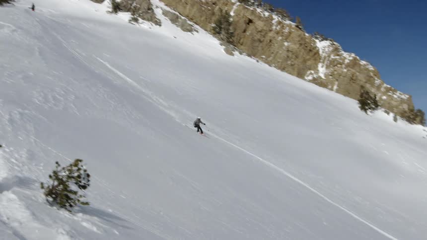 A snowboarder lands on the slope after a jump and boards down