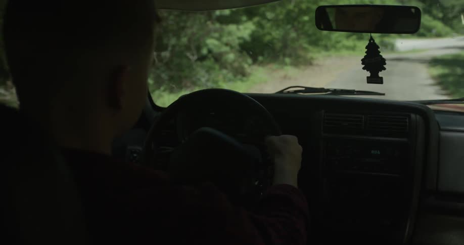 A man drives down a wooded road