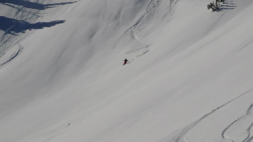 The person skis down the slope fast turning back and forth