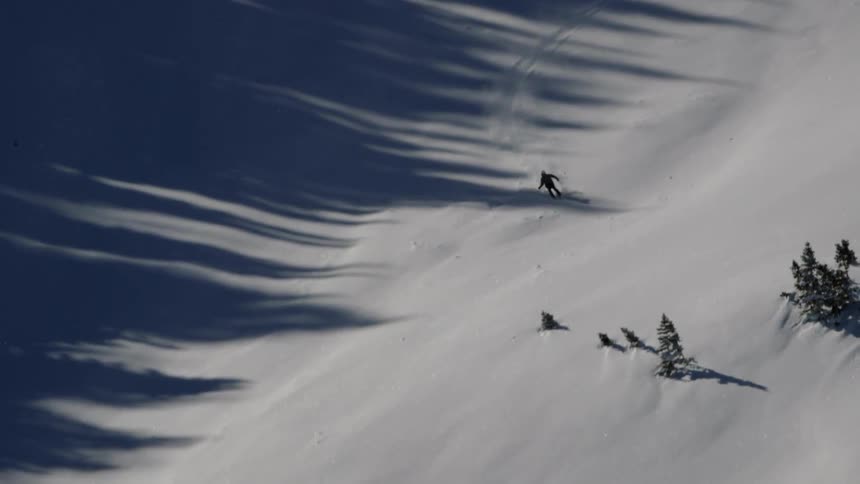 The tall slope has one skier descending