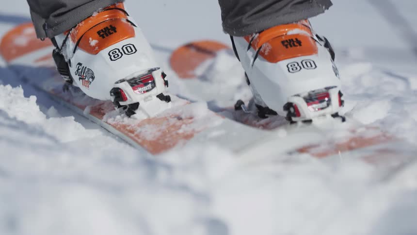 A skier steps onto a ski and snaps his boot in place