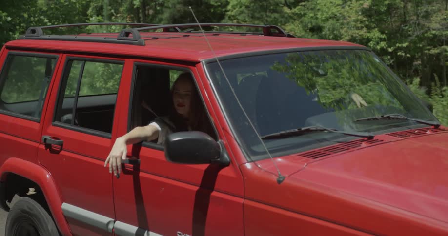 People drive down a road in a red truck