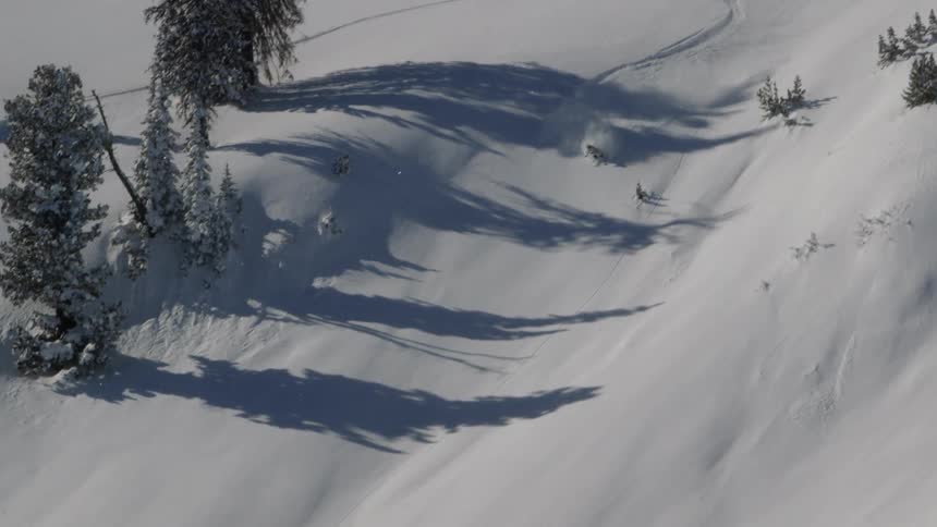 A skier jumps off the top of a hill going down