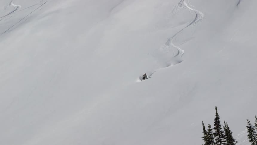 A person skis through fresh powder down a slope