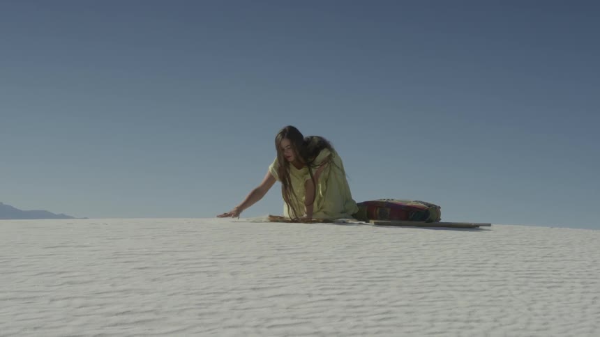 A woman is sitting down on the desert hill