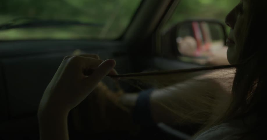 A woman plays with her hair while riding in a vehicle