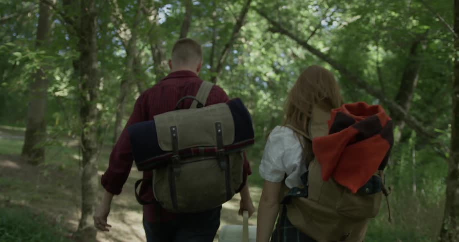 A man and woman walk on a trail carrying gear